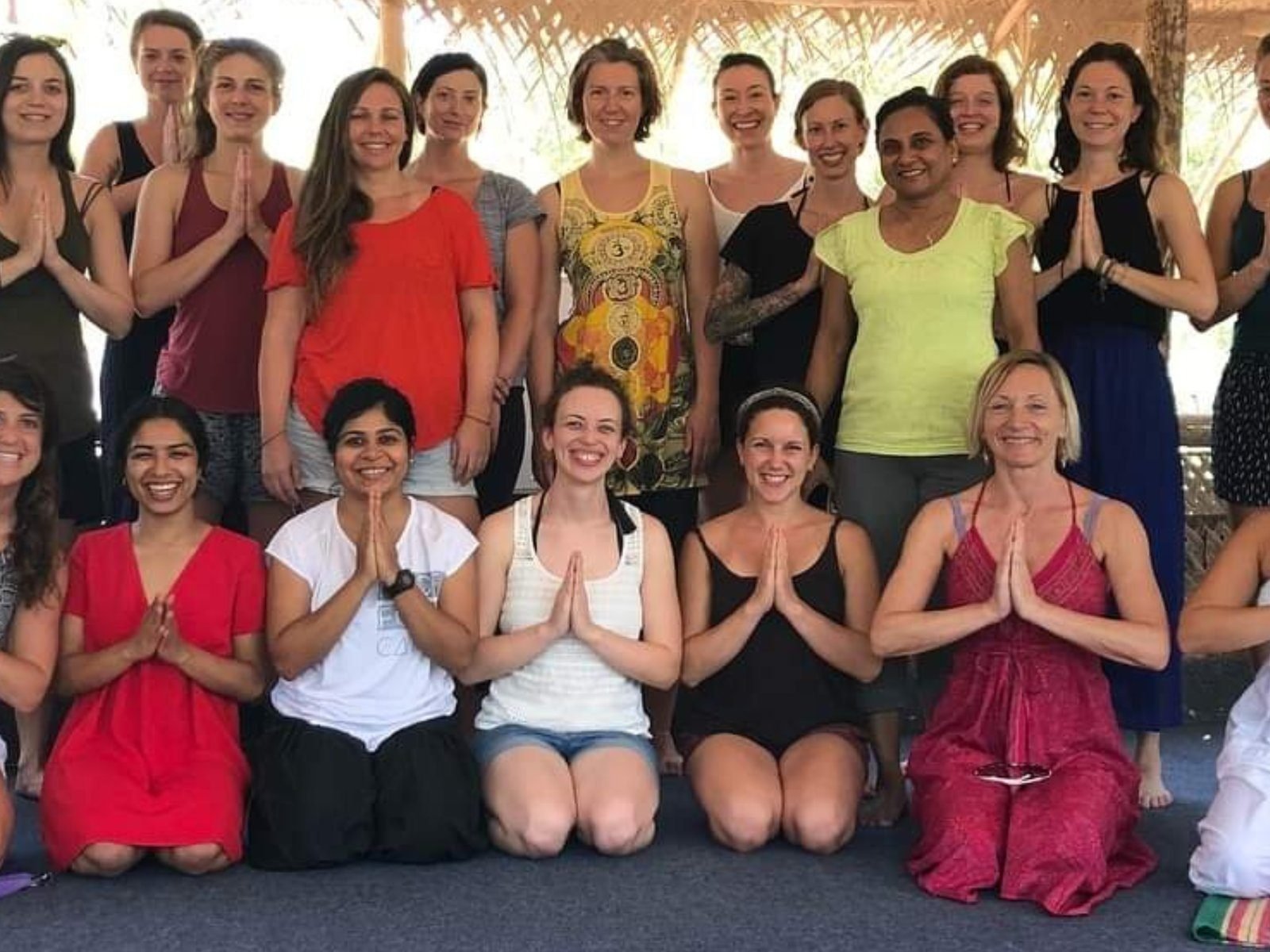 A women's yoga teacher training cohort gathered in a closing namaste circle