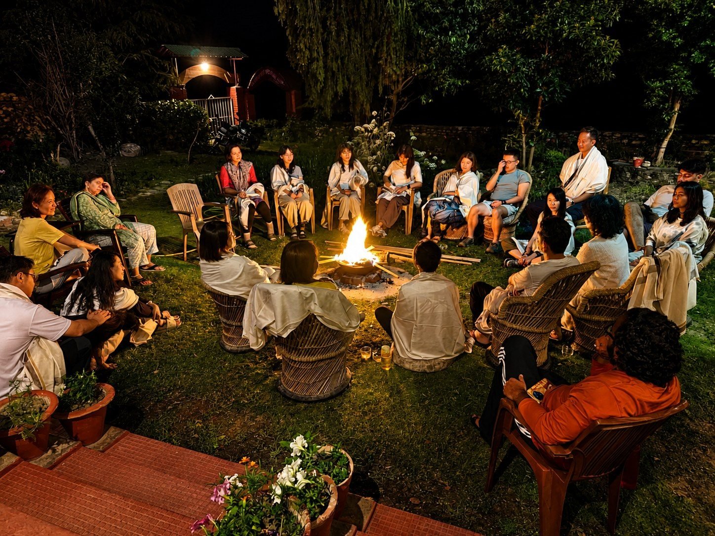 A mixed group sitting together around an evening bonfire in conversation at Our Himalayan Home